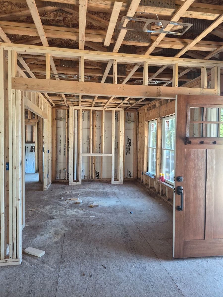 Interior wood framing of a custom home with ceiling joists and craftsman door